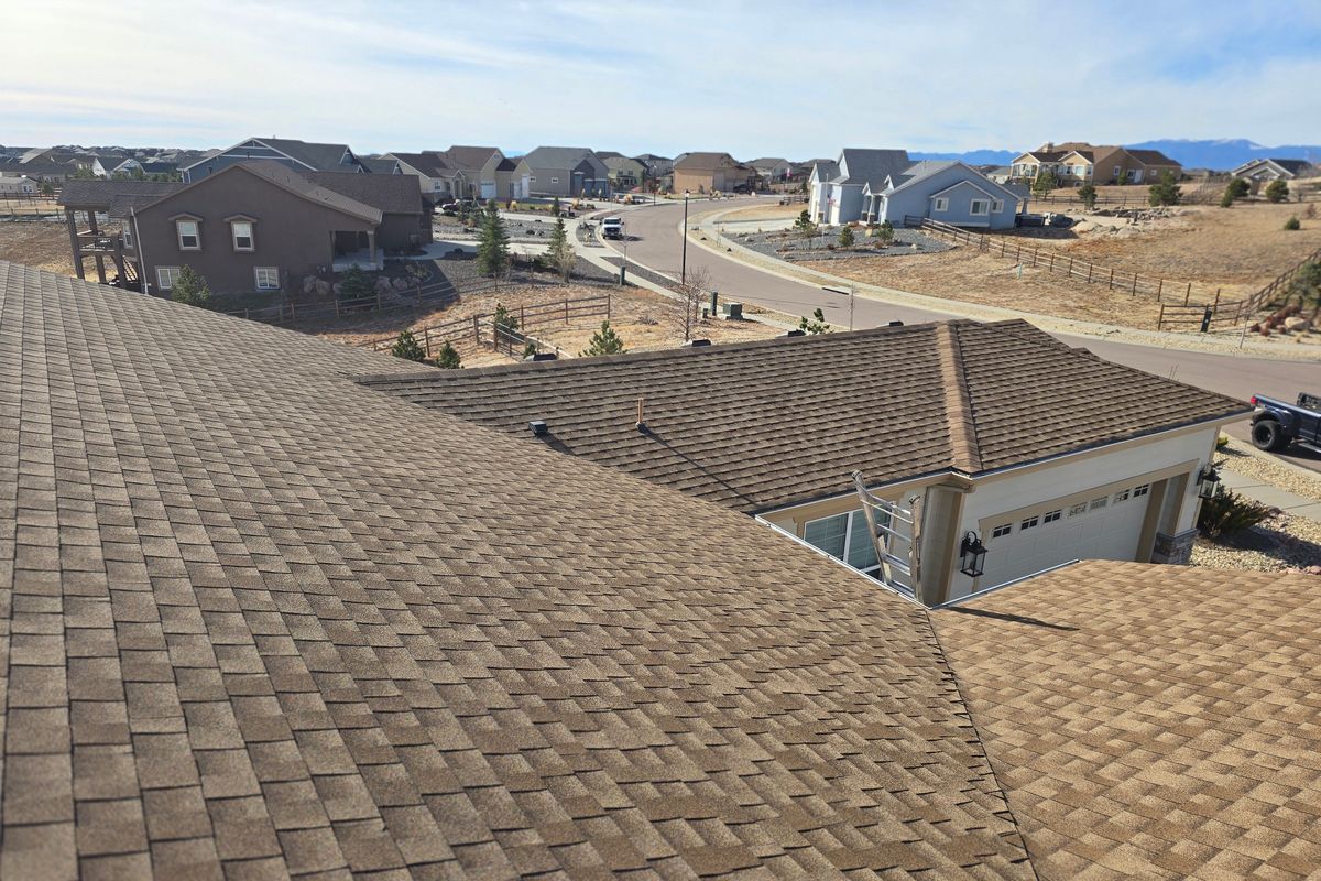 Finished brown shingle roof overlooking a hillside neighborhood